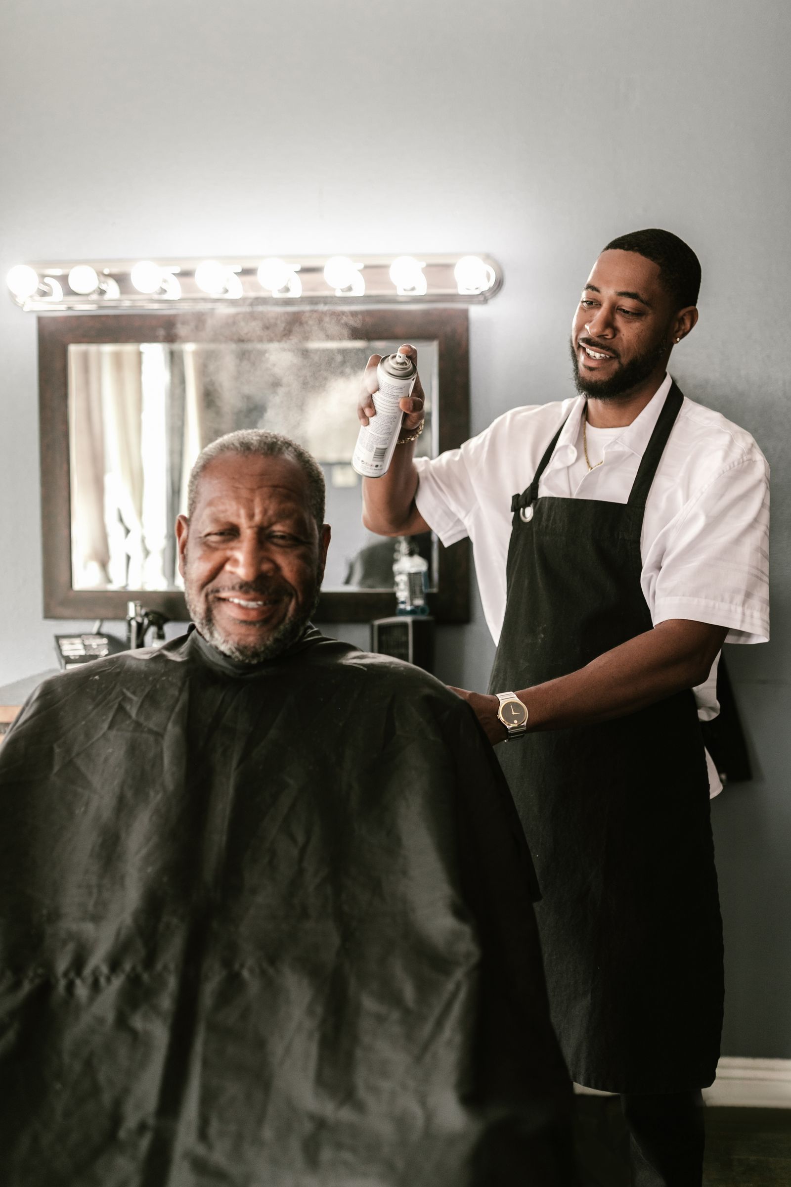 Smilende barber klipper en ældre kunde